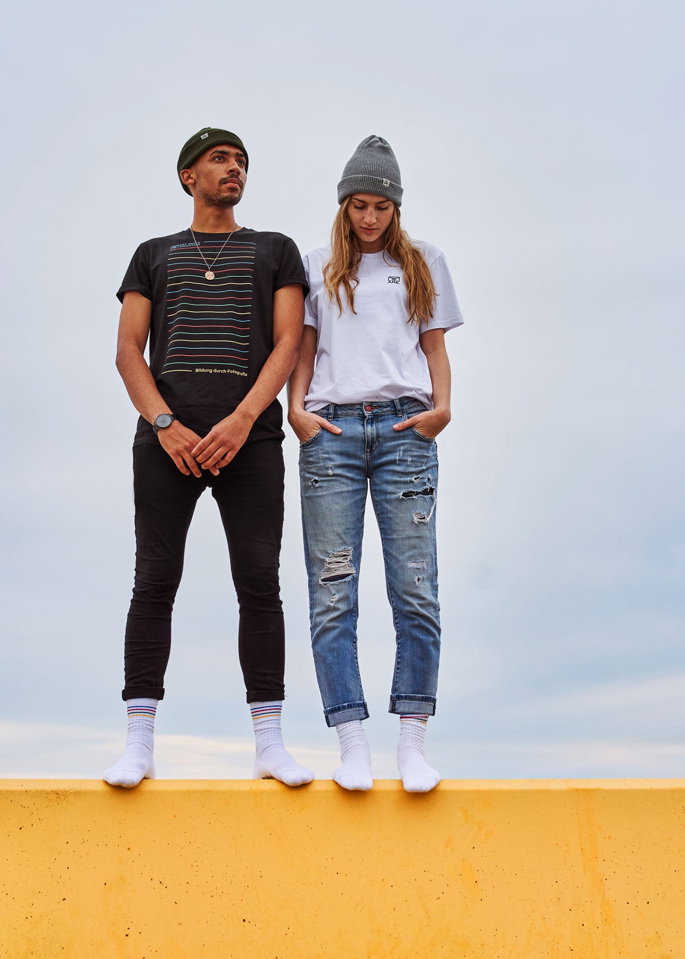 Unsere AME unisex Strickmützen in den Farben schwarz und grau aus 100% GOTS zertifzierter Merino Schurwolle getragen von Wesley und Victorija in Barcelona, hergestellt in Deutschland.