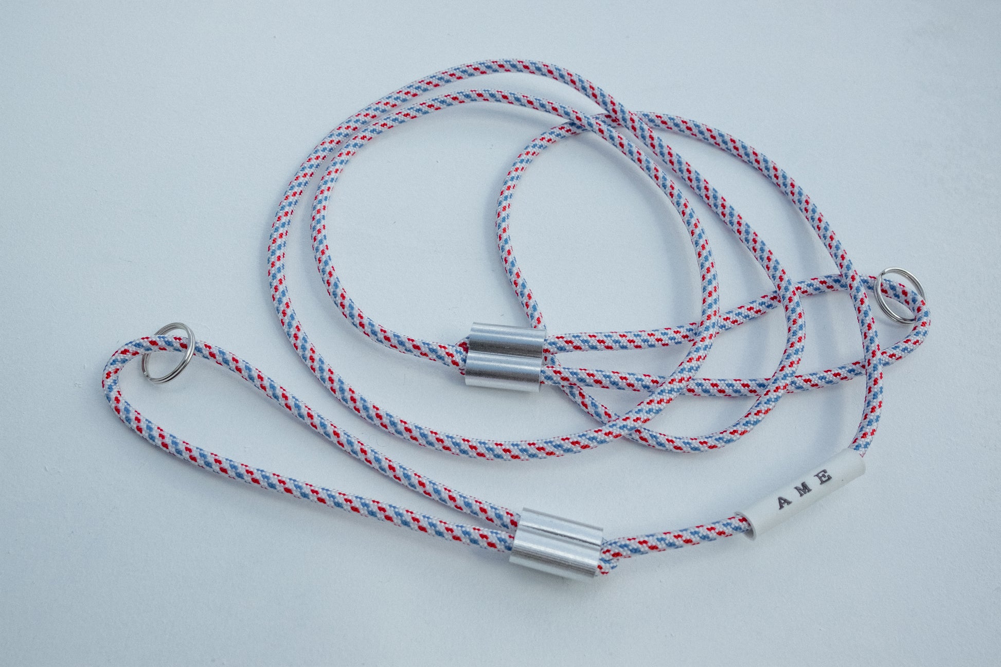 AME x Wolf Camera Strap in der Light Version in den Farben Rot Weiss Blau. Du finanziert 1 Monat Schule mit dem Kauf.