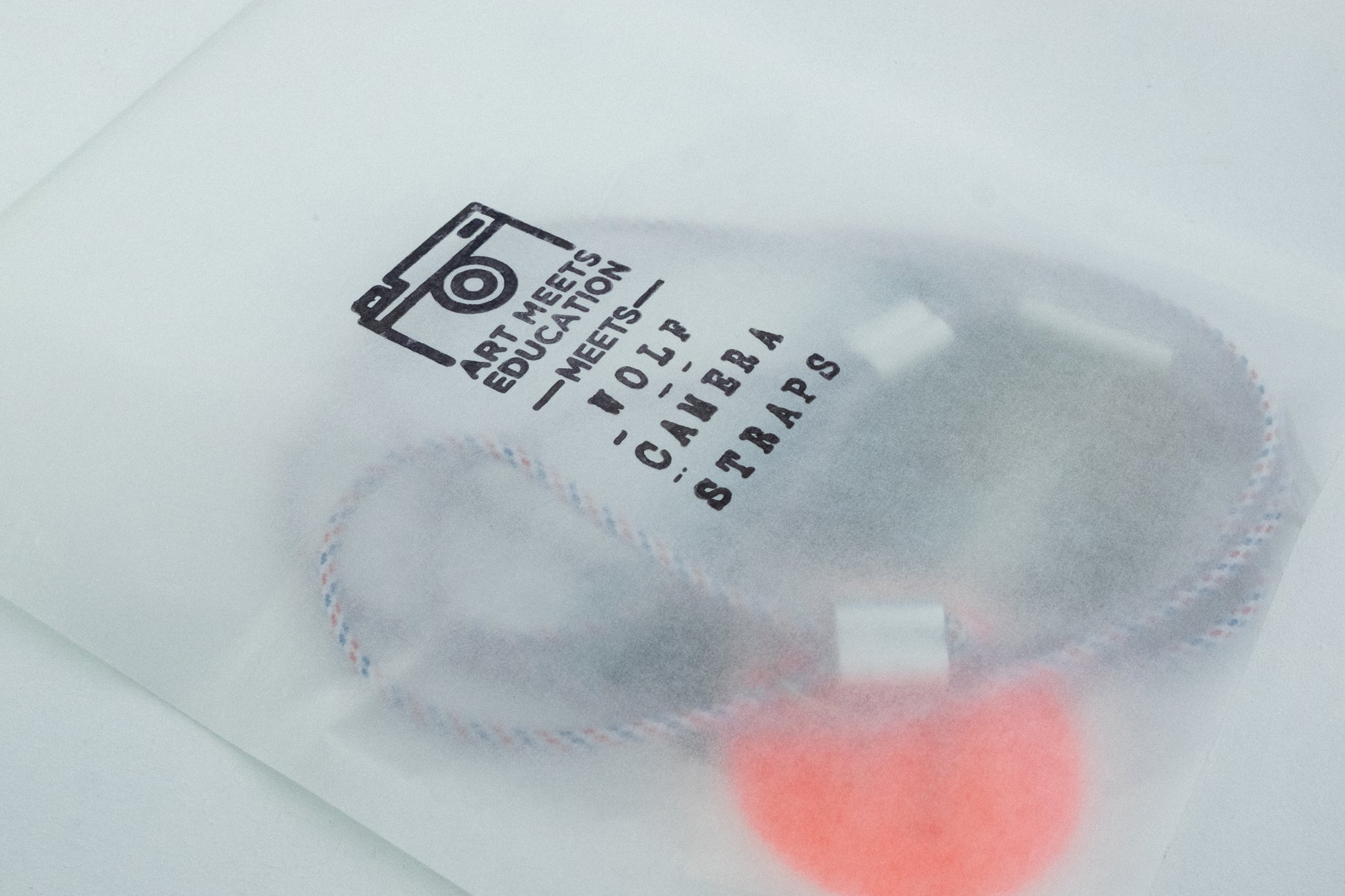 AME x Wolf Camera Strap in der Light Version in der Tüte. Du finanziert 1 Monat Schule mit dem Kauf.